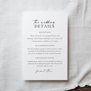 May include: A white wedding details card with elegant script. The card includes information about the reception, accommodations, and transportation. The text is in black, with the words "The wedding DETAILS" at the top.
