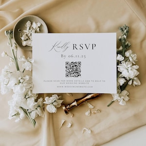 K&ouml;nnte beinhalten: Eine wei&szlig;e RSVP-Karte mit eleganter Schrift und einem QR-Code, umgeben von wei&szlig;en Blumen und einem goldenen Wachssiegel. Die Karte lautet "Kindly RSVP By 06.11.25" und enth&auml;lt eine Website-Adresse f&uuml;r weitere Details.
