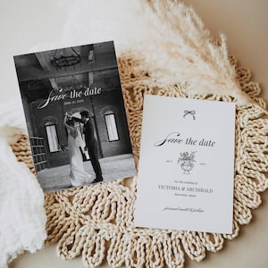 May include: Two white "Save the Date" cards. One card features a black and white photo of a couple dancing. The other card has a floral design and the text "Save the date" in elegant script. The cards are on a beige, woven surface.