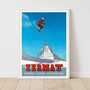 May include: A vintage travel poster advertising Zermatt, Switzerland. The poster features a skier in red jumping over a snowy mountain peak against a blue sky. The text on the poster reads "Zermatt, Schweiz - Suisse - Switzerland".