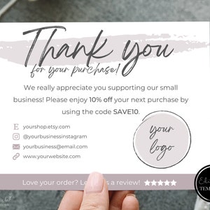 以下が含まれることがあります： グレーと白の水彩画の背景を持つサンキューカード。カードには「ご購入ありがとうございます！」と10％割引コードが記載されています。カードにはロゴと連絡先を記入するスペースもあります。