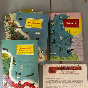 May include: A collection of American Geographical Society Around the World Program booklets featuring maps of New Zealand, Bolivia, and Central America, alongside a printed welcome letter from the program with vintage illustrations and text.