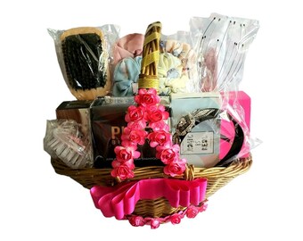 May include: A wicker basket filled with a variety of gifts, including hair accessories, a hair brush, and beauty products. The basket is decorated with pink flowers and a pink ribbon.