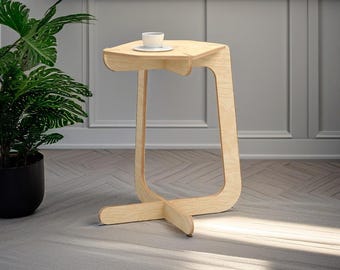 May include: A light wood side table with a curved design and a rounded top. The table is on a light gray rug with a chevron pattern.