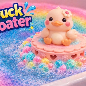 May include: A whimsical bath toy featuring a light peach-colored duck with a flower on its head, sitting on a pink platform. The platform is surrounded by colorful, sparkling bath beads in a rainbow-colored bubbly bath. The text "Duck Floater" is displayed.