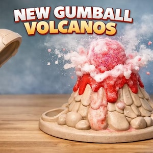 May include: A whimsical gumball volcano toy with a red and pink gumball erupting from the top. The volcano is beige with red lava details. The words "NEW GUMBALL VOLCANOS" are displayed above the volcano.