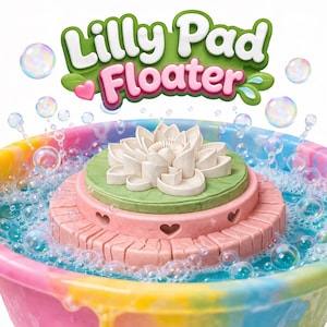 May include: A colorful toy with the text "Lilly Pad Floater". The toy features a multi-tiered design with a white lotus flower on top, surrounded by bubbles. The base is pink, green, and white.