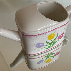 Könnte beinhalten: Weiße Keramik-Gießkanne mit einem rosa-weißen Blumendesign mit Tulpen. Die Kanne hat einen Ausguss und einen Griff.