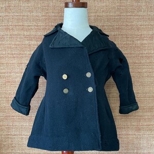 May include: A vintage black wool coat with a double-breasted design and gold-colored buttons. The coat features a notched collar and folded cuffs. The coat is displayed on a mannequin.