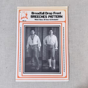 May include: A vintage sewing pattern for Broadfall Drop Front Breeches. The pattern includes waist sizes 30 to 42 inches. The cover features a graphic of two men wearing the breeches. The pattern has an orange and black border.