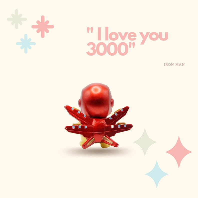 May include: A red and gold Iron Man figurine with the text "I love you 3000" in pink letters. The figurine is facing away from the camera and has its arms outstretched.