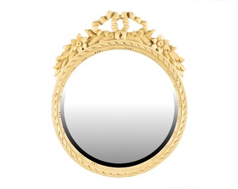 May include: A round, gold-toned mirror with a decorative, carved frame. The frame features a floral design with leaves and flowers, and a ribbon at the top.