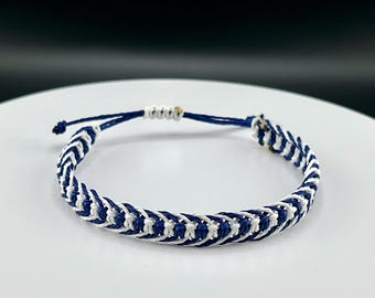 May include: A blue and white braided friendship bracelet with a simple knot closure.