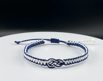 May include: A blue and white braided friendship bracelet with a knot in the center.