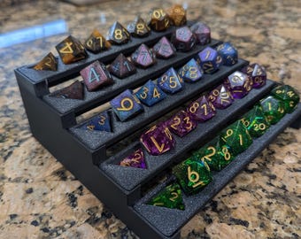 May include: A black plastic dice tray with multiple levels to hold different colored dice. The dice are iridescent and have gold numbers.