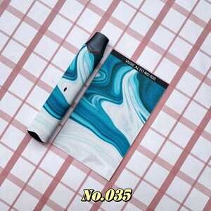 以下が含まれることがあります： 青と白の大理石模様のデザインの黒と白のVapeデバイスと、それに合わせた長方形のカード。カードには「Vuse Alto No. 035」と書かれています。「No. 035」の数字も下部に金色で印刷されています。