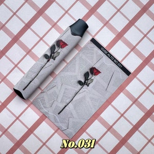 以下が含まれることがあります： 黒とグレーのVAPEペンと、新聞の印刷が施されたグレーの背景に赤いバラのデザインが施されたお揃いのカード。カードには「VUSE ALTO NO. 031」と書かれており、「No.031」の数字も表示されています。