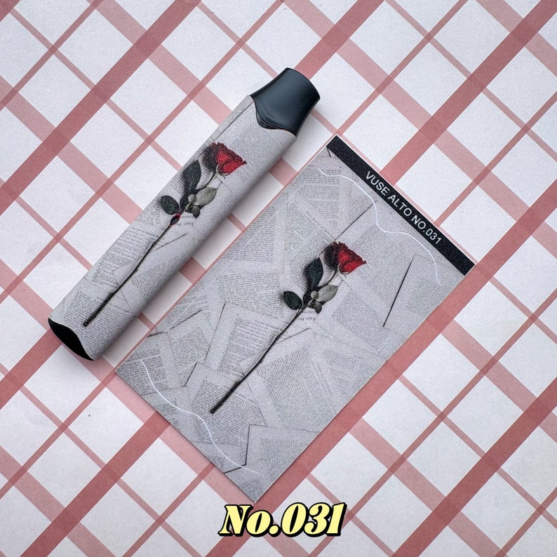 以下が含まれることがあります： 黒とグレーのVAPEペンと、新聞の印刷が施されたグレーの背景に赤いバラのデザインが施されたお揃いのカード。カードには「VUSE ALTO NO. 031」と書かれており、「No.031」の数字も表示されています。