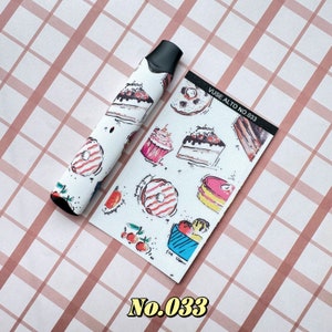 以下が含まれることがあります： 白いVapeペンと、ケーキ、ドーナツ、アイスクリームなどのカラフルなデザート模様で飾られたマッチングカード。カードには「Vuse Alto No. 033」の文字が入っています。ペンはピンクと白のチェック柄の背景にあります。