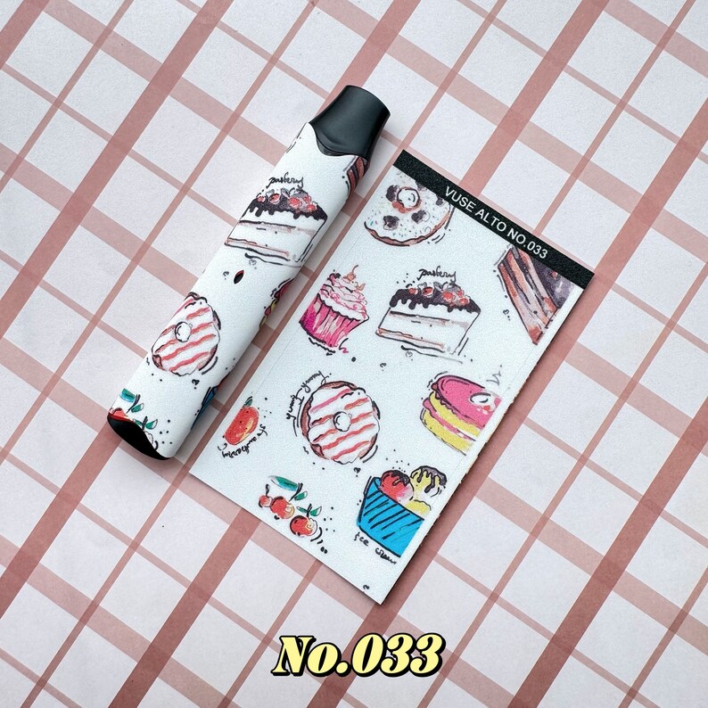 以下が含まれることがあります： 白いVapeペンと、ケーキ、ドーナツ、アイスクリームなどのカラフルなデザート模様で飾られたマッチングカード。カードには「Vuse Alto No. 033」の文字が入っています。ペンはピンクと白のチェック柄の背景にあります。