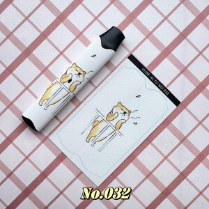 以下が含まれることがあります： 黒い先端が付いた白いVAPEペンと、それに合わせたカード。どちらも、音符が付いた漫画の柴犬のデザインが特徴です。カードには「VUSE ALTO NO.032」と書かれています。背景はピンクと白のチェック柄です。