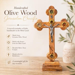 Puede incluir: Crucifijo de Jerusalén de madera de olivo hecho a mano con un corpus plateado. La cruz está incrustada con piedras y presenta el texto "Handcrafted Olive Wood Jerusalem Crucifix". Un regalo significativo para cualquier ocasión.