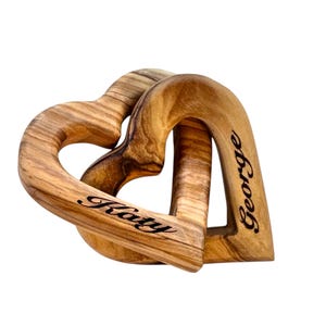 May include: Two interlocking wooden hearts with the names "Katy" and "George" engraved on them.