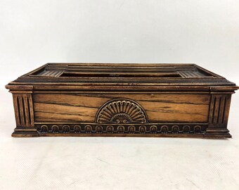 May include: A rectangular tissue box cover with a dark brown wood grain finish. The front panel features a central semi-circular fan-shaped relief carving, flanked by vertical fluted columns at the corners and a decorative arched border along the base.