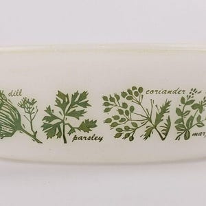 May include: White ceramic baking dish with a green and white herb design. The herbs are labeled "dill", "parsley", "coriander", and "marjoram".