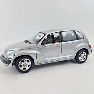 Könnte beinhalten: Silbernes Modellauto mit schwarzen Reifen und Chromfelgen. Das Auto hat eine abgerundete Karosserie mit schwarzen Innensitzen. Das Auto ist ein PT Cruiser.