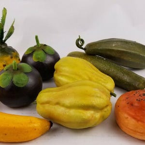 May include: A collection of artificial fruits and vegetables, including a yellow banana, a green cucumber, a brown and green mangosteen, a yellow papaya, a pineapple, and a brown and orange fruit.