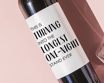 May include: A dark wine bottle with a white label that reads "THIS IS TURNING INTO THE LONGEST ONE-NIGHT STAND EVER" is positioned diagonally on a pink background. Two wine glasses are also present. The image has strong shadows.