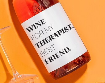 May include: A bottle of rose wine with a white label that reads "Wine for my therapist best friend." The bottle is surrounded by four clear wine glasses on a bright orange background.