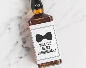 May include: A brown glass bottle with a white label that says "Will you be my groomsman?" with a black bow tie illustration. The bottle is labeled "Old No. 7 Brand".