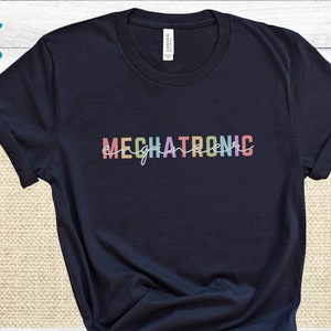 May include: A navy blue t-shirt with the word "MECHATRONIC" printed in rainbow colors.