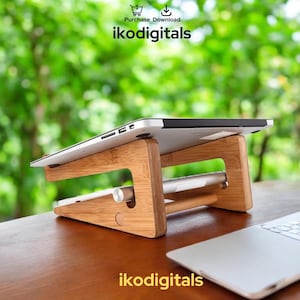 Könnte beinhalten: Ein Laptop-Ständer aus Holz mit einer silbernen Metallstange zum Halten eines Stifts. Der Ständer ist aus natürlichem Bambus gefertigt und wurde entwickelt, um einen Laptop für eine bessere Ergonomie zu erhöhen.