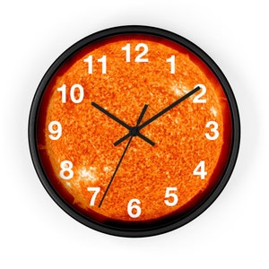 May include: A black framed clock with a sun image as the clock face. The numbers 1 through 12 are white and the clock hands are black.