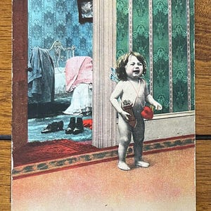 May include: A vintage Valentine's Day postcard featuring a young child dressed as Cupid, holding a bow and arrow and a heart. The child is crying and the caption reads "Another Job Finished."