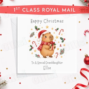 May include: A square white greeting card featuring a brown capybara wearing a red Santa hat and a red and white patterned scarf. The capybara holds a gift box. Text reads Happy Christmas To A Special Granddaughter Ellie with holly and candy canes.