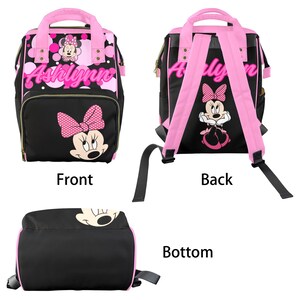 May include: Black and pink backpack featuring Minnie Mouse. The front has a large Minnie Mouse face with a pink polka dot bow. The name "Ashlynn" is written in pink script. The back has pink straps and a Minnie Mouse graphic.