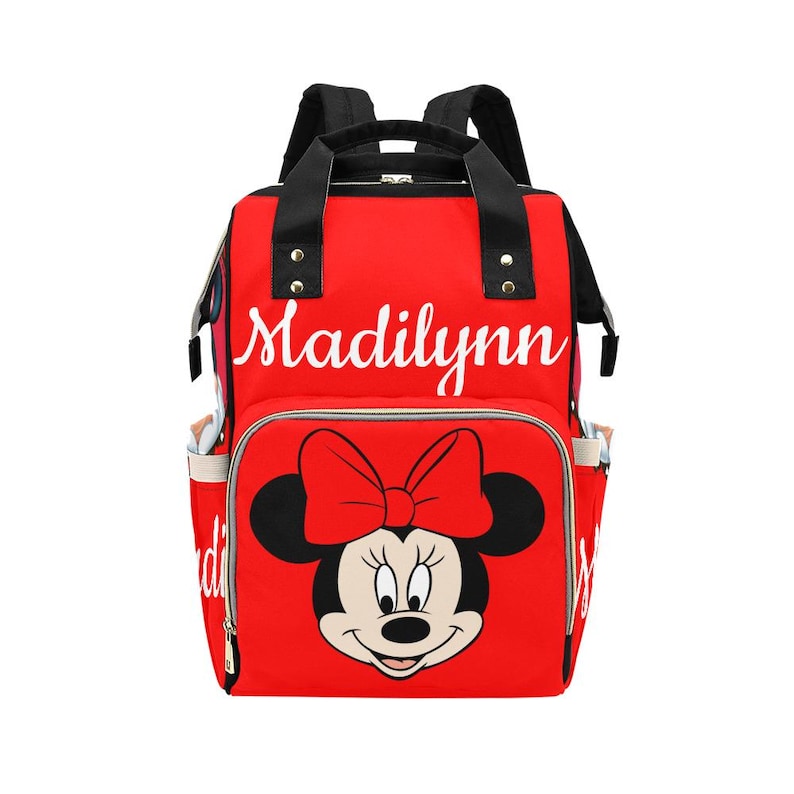 May include: Red backpack featuring a Minnie Mouse graphic with a large bow. The backpack has black straps and handles, side pockets, and the name "Madilynn" in white script across the top. A stylish and functional bag.