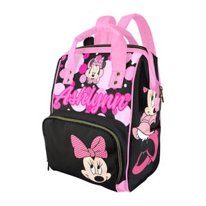 May include: A black and pink backpack featuring Minnie Mouse. The backpack has pink handles, straps, and accents. The name "Ashlynn" is printed in pink script on the front. Minnie Mouse is depicted with a polka dot bow and dress.