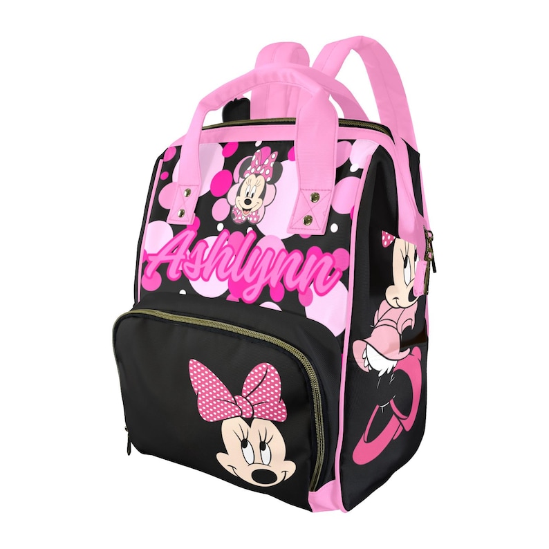 May include: A black and pink backpack featuring Minnie Mouse. The backpack has pink handles, straps, and accents. The name "Ashlynn" is printed in pink script on the front. Minnie Mouse is depicted with a polka dot bow and dress.