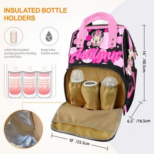 May include: Black and pink insulated baby bottle holder backpack with a Minnie Mouse design. The bag has a pink handle and the name "Ashlynn" in pink. It measures 16 inches (40.5 cm) high, 10 inches (25.5 cm) wide, and 6.5 inches (16.5 cm) deep.