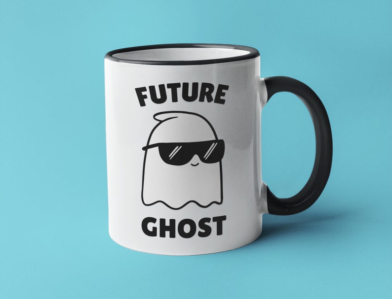 May include: White ceramic mug with a black rim and handle. The mug has a black and white illustration of a ghost wearing sunglasses and the text "FUTURE GHOST".