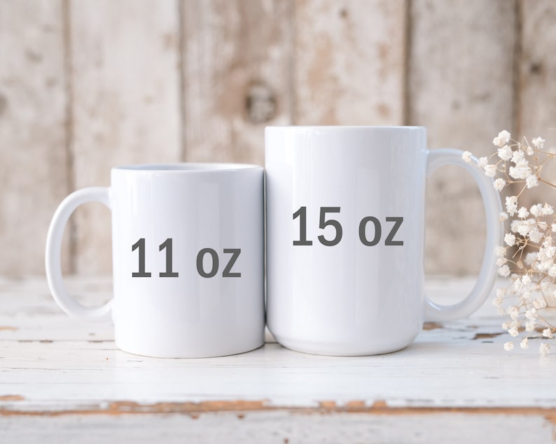 May include: Two white ceramic mugs with black text. The mug on the left says "11 oz" and the mug on the right says "15 oz".