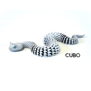Puede incluir: Una figura de serpiente articulada en blanco y negro con un patrón de escamas texturizado y puntiagudo y ojos azul brillante. La palabra CUBO está impresa en letras mayúsculas negras cerca de la cola de la serpiente, en una pose en forma de S.