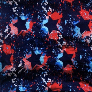 May include: A navy blue fabric with a repeating pattern of white, red, and blue stars. The stars are outlined in black and have a splatter paint effect.