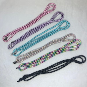 May include: Six different shoelaces with glitter. The shoelaces are in various colors, including pink, purple, blue, and rainbow.