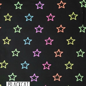 May include: Black fabric with a repeating pattern of multi-colored outlined stars. The fabric has a ruler with the word "BLACKCAT" printed on it.